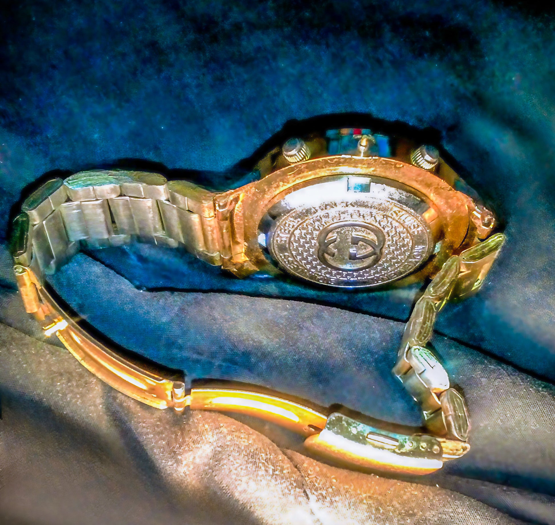 Gold and silver Gucci watch on a textured blue surface